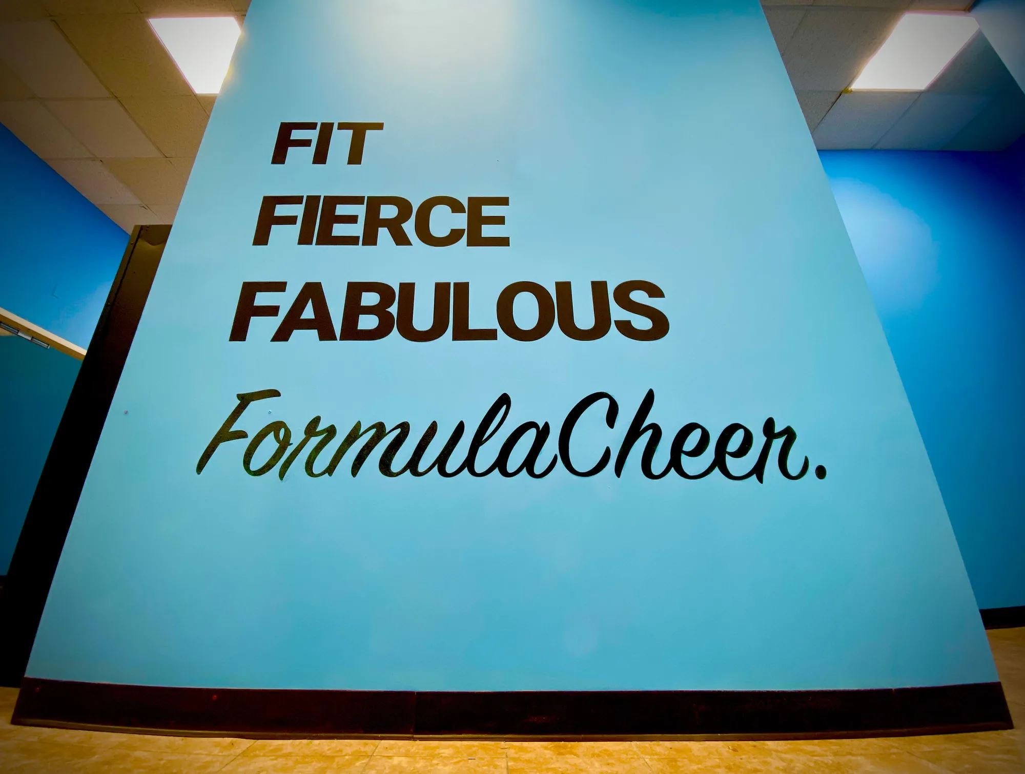 The Formula Cheer gym wall, painted with Fit Fierce Fabulous above the Formula Cheer script logo